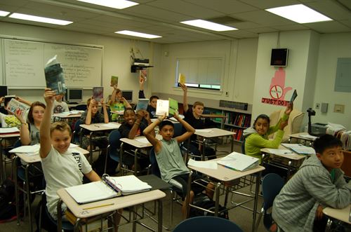 Students holding books in air